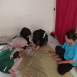 Tampak mahasiswa tergabung dalam Kelompok Kuliah Kerja Nyata (KKN) T-18 Universitas Nurul Huda sedang belajar menganyam tikar purun saat mengunjungi pengrajin tikar purun asli Desa Kota Negara Timur. 25 Juli 2024.