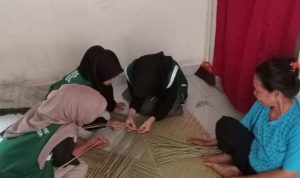 Tampak mahasiswa tergabung dalam Kelompok Kuliah Kerja Nyata (KKN) T-18 Universitas Nurul Huda sedang belajar menganyam tikar purun saat mengunjungi pengrajin tikar purun asli Desa Kota Negara Timur. 25 Juli 2024.
